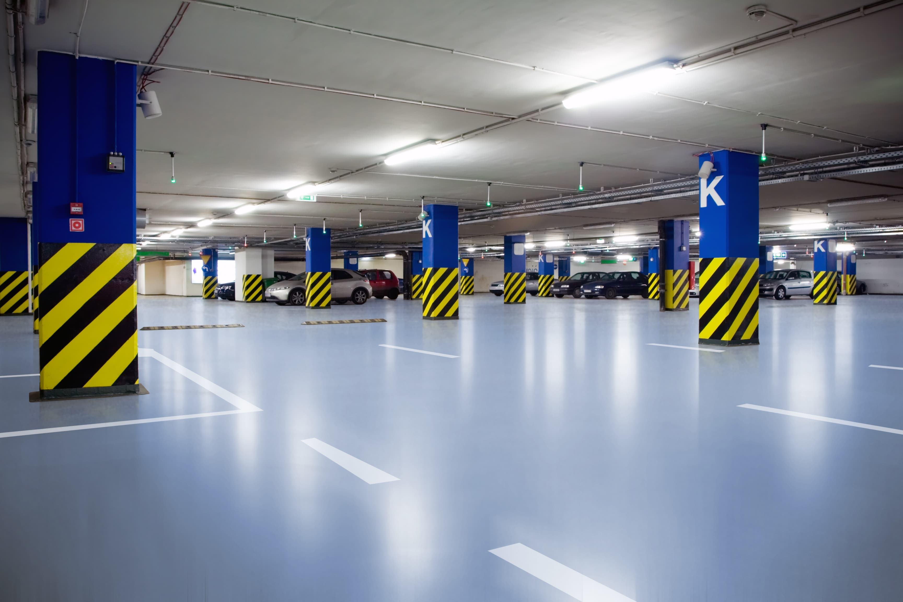 Parqueo subterráneo con piso poliuretano Tecnofloor PU-3060, columnas señalizadas en azul y demarcación de plazas