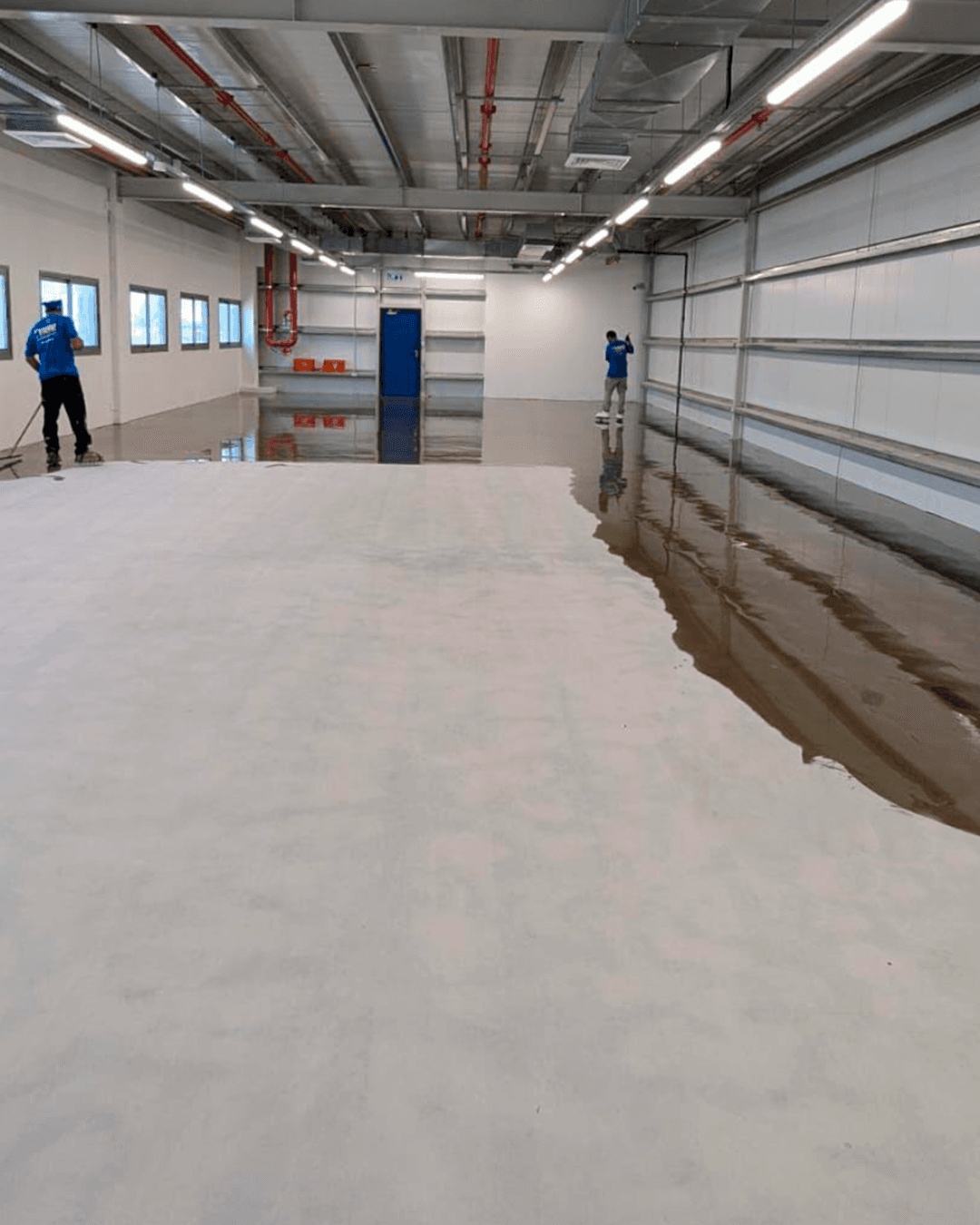 Aplicadores instalando sistema epóxico autonivelante en planta industrial