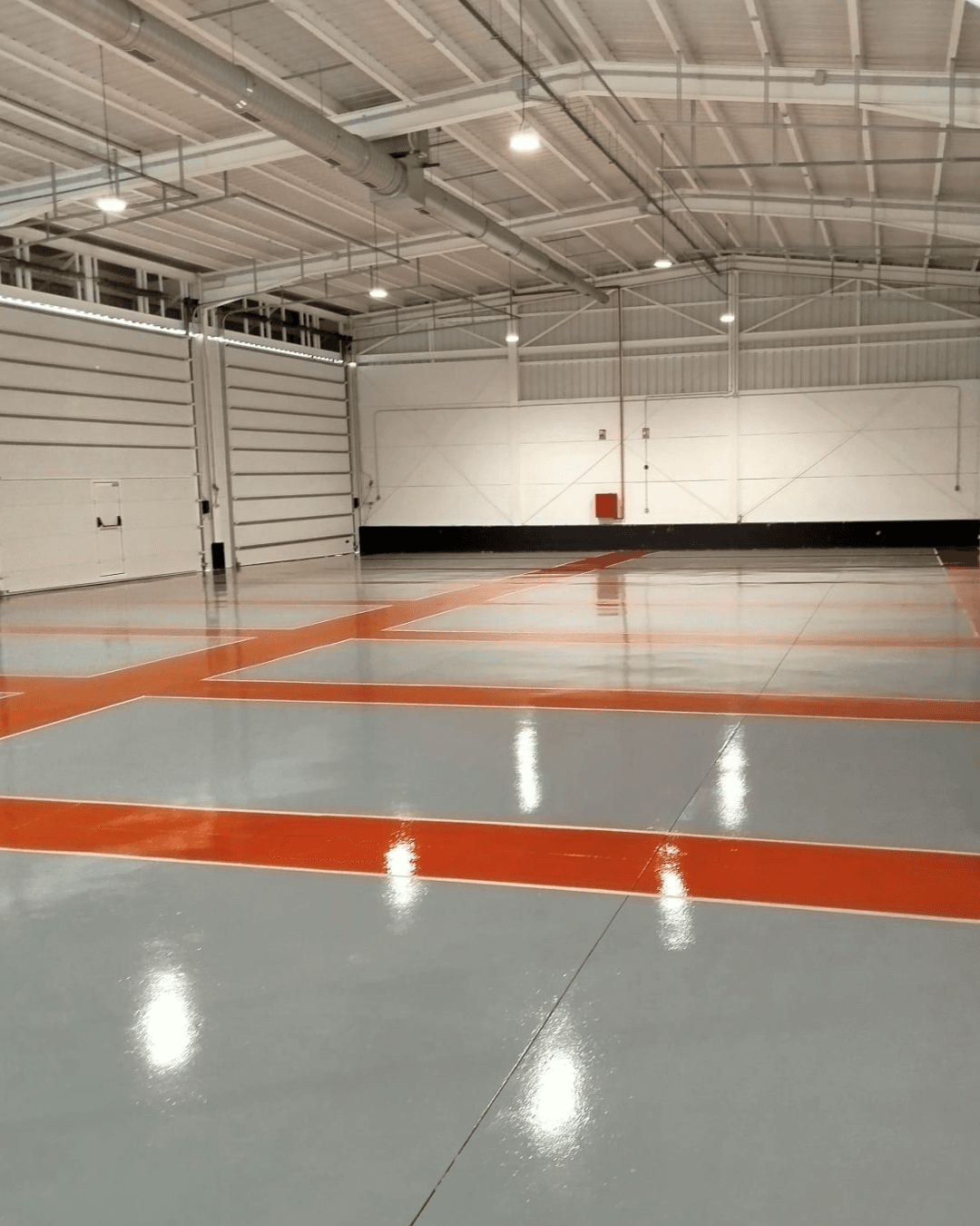 Piso epóxico industrial con bandas grises y naranjas para demarcación de tráfico
