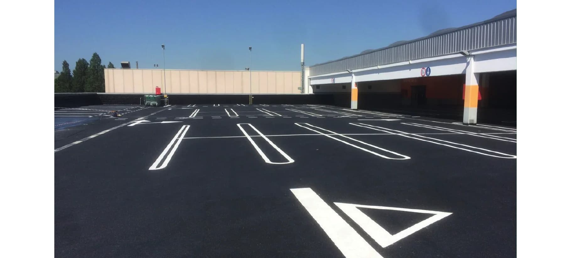 Parqueo exterior con marcas viales blancas y acabado Tecnotop 2C bajo cielo despejado