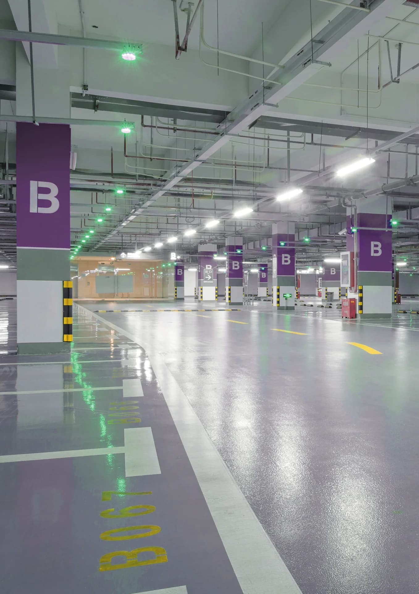 Parqueo cubierto con pilares morados, piso epóxico gris brillante y luces verdes Tecnotop S-3000